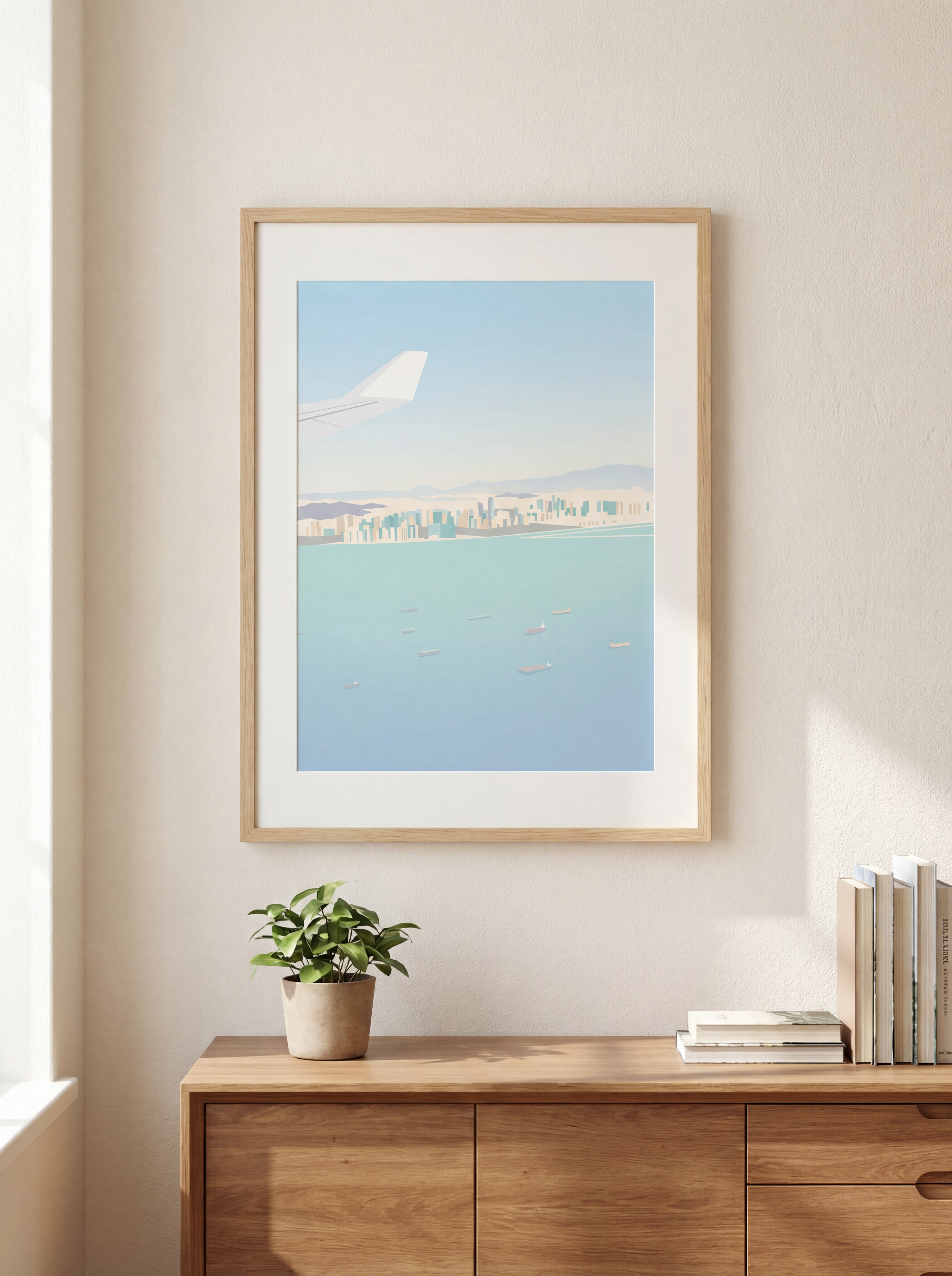 Framed artwork of an airplane over water with a cityscape, displayed on a wall above a wooden cabinet.