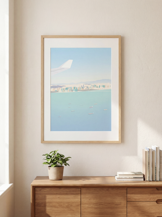 Framed artwork of an airplane over water with a cityscape, displayed on a wall above a wooden cabinet.