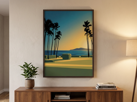 Framed artwork of a tropical landscape with palm trees and a sunset on a wall above a wooden cabinet.